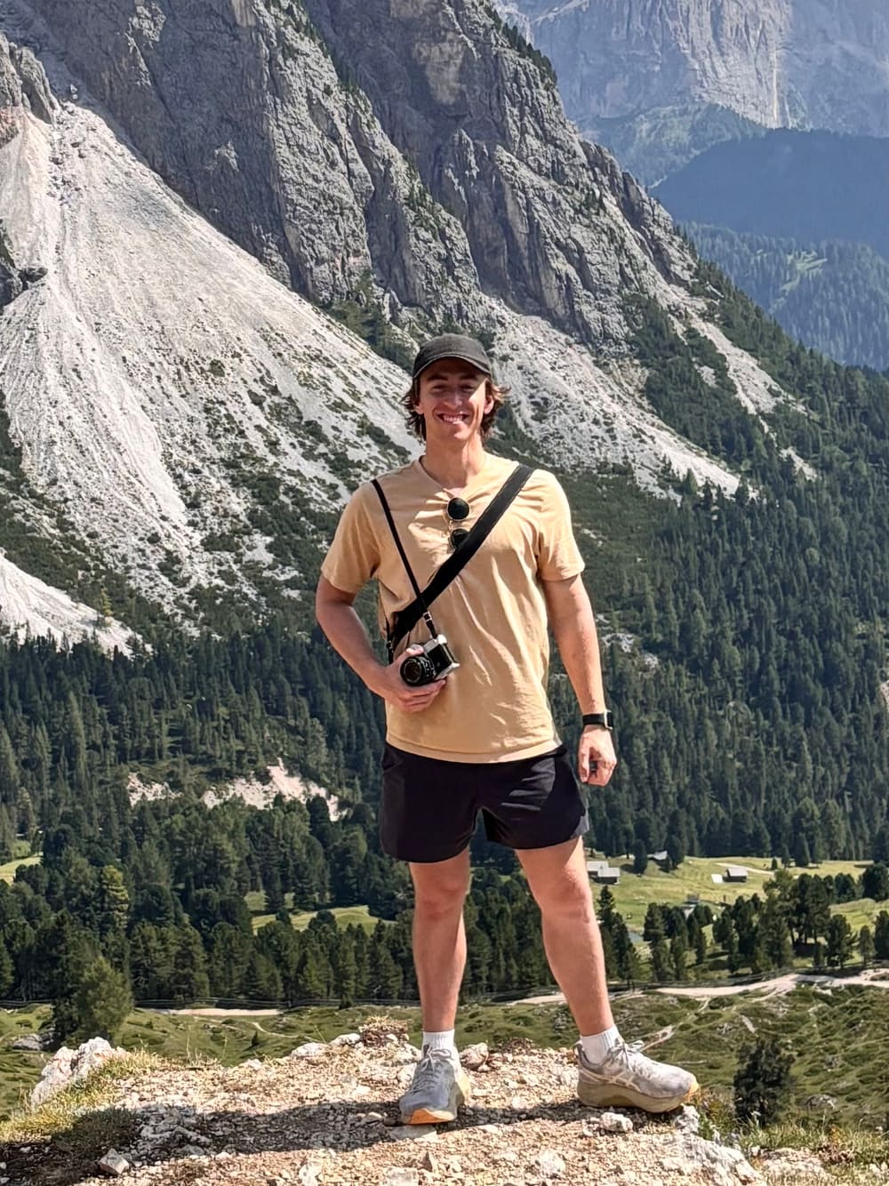 Tom Bannerman standing on a ridge in the Dolomites with a film camera
